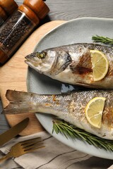 Delicious baked fish served on grey wooden table, top view