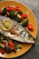 Delicious baked fish and vegetables on grey background, top view