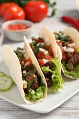 Delicious tacos with meat and vegetables on wooden table, closeup