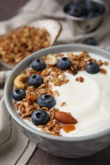 Bowl with yogurt, blueberries and granola on grey table, closeup