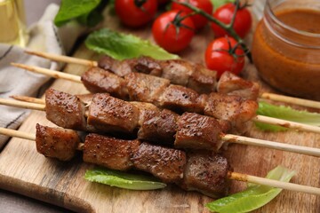 Tasty cooked marinated meat served with sauce and tomatoes on grey table, closeup