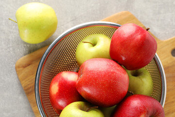 Fresh ripe apples in colander on light grey table, top view