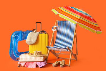 Suitcases with beach accessories, binoculars and deck chair on color background
