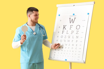 Male ophthalmologist with occluder and eye test chart on yellow background