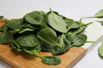Board with fresh spinach leaves on white table, closeup
