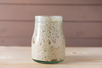 Sourdough starter in glass jar on wooden table