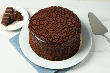 Delicious truffle cake, chocolate pieces and server on white marble table