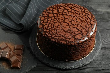 Delicious truffle cake and chocolate pieces on black wooden table