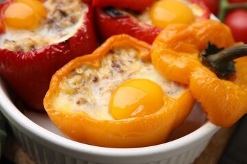 Delicious stuffed peppers with eggs in bowl on table, closeup