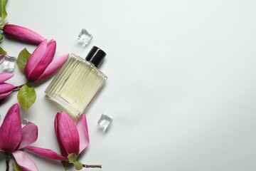 Beautiful pink magnolia flowers, bottle of perfume and ice cubes on light grey background, flat...