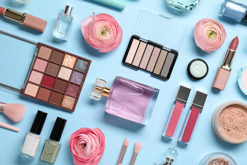 Flat lay composition with different makeup products and beautiful spring flowers on light blue...