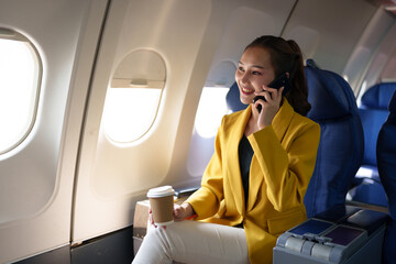 Young woman, business woman in a yellow suit is using a smartphone to communicate with customers...