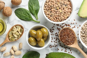 Different products and seeds high in healthy fats on white marble table, flat lay