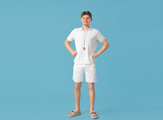 Male lifeguard with whistle on blue background