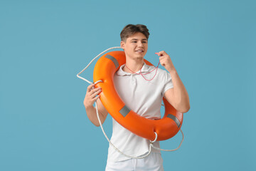 Male lifeguard with lifebuoy ring and whistle on blue background