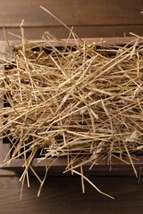 Dried straw in crate on wooden table, top view
