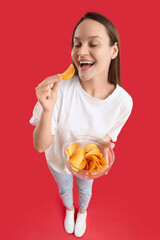 Young woman with bowl of potato chips on red background