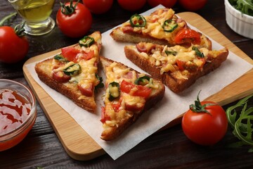 Tasty pizza toasts and ingredients on wooden table