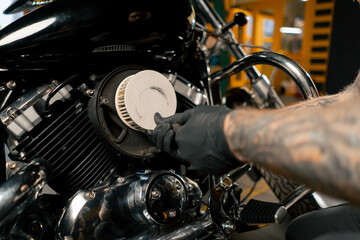 Obraz premium close up In a motorcycle repair shop mechanic takes out a filter to replace it with a new one
