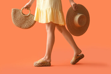 Young woman with straw bag and hat on orange background