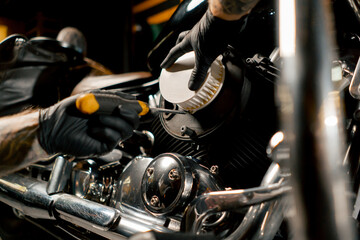 close up In a motorcycle repair shop mechanic takes out a filter to replace it with a new one