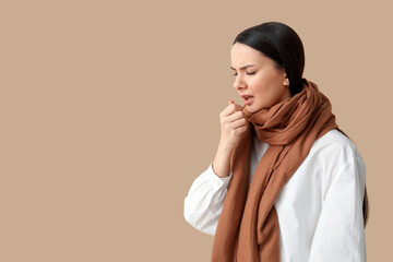 Beautiful young woman in scarf suffering from sore throat on brown background