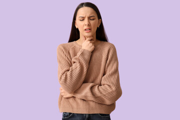 Beautiful young woman suffering from sore throat on lilac background
