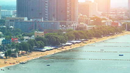 Naklejka premium At sunset, Jomtien Beach bursts with tropical colors, as the sun's fiery embrace meets the azure waters, creating a mesmerizing, postcard-perfect scene. Pattaya, Thailand. Aerial view drone. 