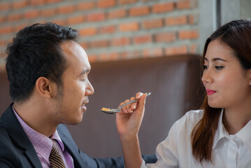 A woman is feeding a man with a spoon.