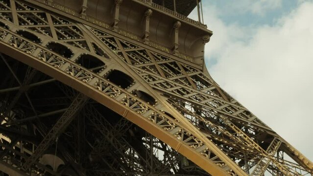 Handheld pan tracking detail shot of The Eiffel Tower Tour Eiffel in Paris, France, Europe. Golden hour spring summer sunny overcast day. Historic iconic city centre landmark architecture skyscraper.