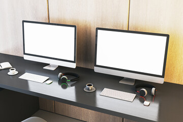 Two empty white gaming computer monitor on desk with coffee cups and headsets. Place for your advertisement. Gaming club concept. Mock up, 3D Rendering.