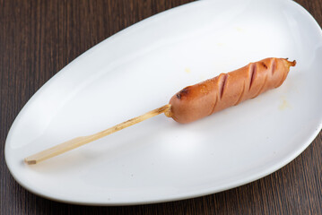 One grilled sausage on a white plate.