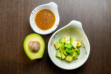 One avocado and a bowl of diced avocado with a side of spicy mayo.