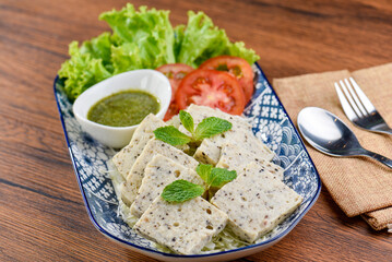 A plate of Vietnamese pork sausage with lettuce, tomatoes, and mint leaves.