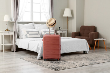 Suitcase with hat in interior of light hotel room