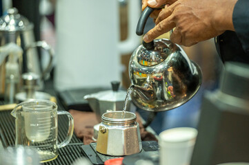 Pouring hot water into a coffee maker to make coffee.