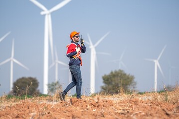 Male man engineer inspection posing check control wind power machine in out door wind energy factory. Young man technician professional worker check wind power machine for maintenance turbine
