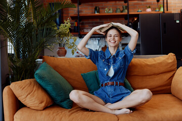 Happy woman relaxing on orange couch with hands behind head and smiling in cozy living room interior