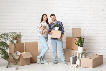 Young happy couple holding belongings in their new house