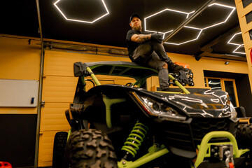 In a motorcycle repair shop, a master sits on top of a large quad bike, extreme riding © Guys Who Shoot