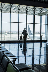 One man standing at the airport gate waiting his flight with delay or canceled. Traveler people...