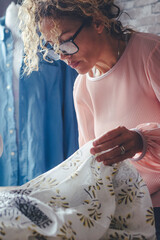 Mature dressmaker woman sews clothes on sewing machine. Concentrated seamstress and her hand...