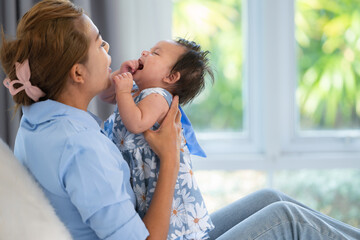 A mother plays with her little daughter in a bedroom full of warmth and family.