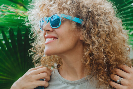 Happy female tourist with backpack enjoy nature park and smile agains a green big tropical leaf background. People and spring vacation. outdoor leisure activity. Portrait of happy woman outdoors