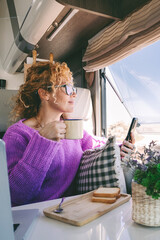 One tourist woman admire the beach inside her modern camper van and use mobile phone. Summer transport holiday vacation people with motor home. Alternative home and lifestyle. Vanlife lady leisure
