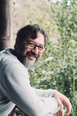 Side portrait of happy and cheerful mature young man enjoying nature outside home relaxing on the terrace. Joy people on vacation or house leisure activity alone. Wearing glasses bearded male outdoor