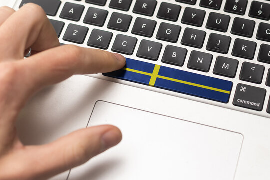 Online International Business concept: Computer key with the Sweden on it. Male hand pressing computer key with Sweden flag - Powered by Adobe