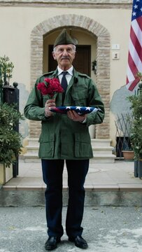 American Military Veteran Waits Outside House With Flowers And Flag