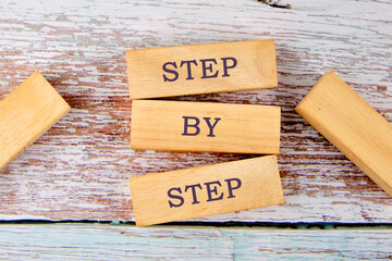 Concept Step by Step text on wooden blocks on old boards