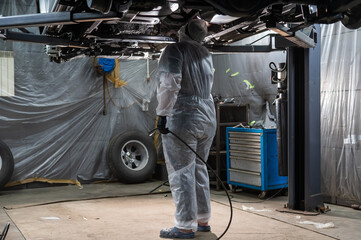 The master sprays an anti-corrosion compound on the bottom of the car. 